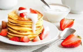 Оладьи с клубникой и сметаной на столе