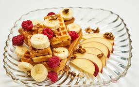 Сладкие вафли на тарелке с бананом, малиной и яблоком