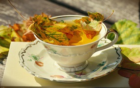 Красивая чашка чая на столе с осенними листьями