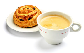 Чашка кофе с булочкой на столе