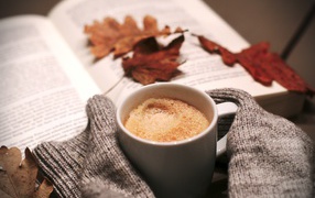 Чашка горячего кофе на столе с книгой 