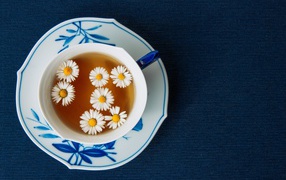 Чашка горячего чая с ромашкой на столе