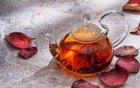 Стеклянный чайник на столе с листьями