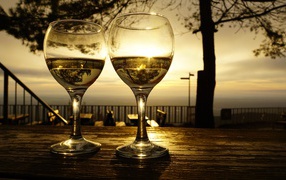 Два бокала белого вина на столе в лучах солнца