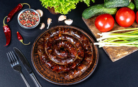 Аппетитная домашняя колбаса на столе со специями и овощами