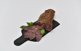 Cured meat on a board on a gray background