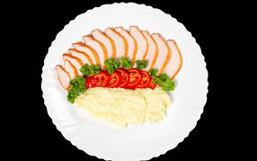 Ham on a large white plate with potatoes and tomatoes