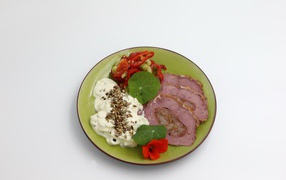 Мясо с соусом и овощами на тарелке на сером фоне