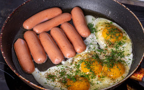 Sausages with scrambled eggs in a pan