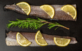 Свежее филе рыбы с лимоном и розмарином на черном фоне