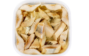 Кусочки селедки в банке с маслом на белом фоне 