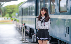 Красивая девушка азиатка в костюме стоит у поезда