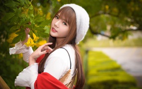 Девушка в берете стоит у куста с желтыми цветами