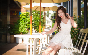 Девушка в белом платье сидит на лавочке