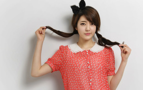 Девушка азиатка в платье стоит у стены 