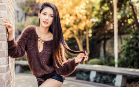 Девушка азиатка в черных шортах у стены