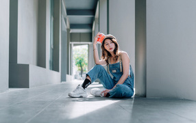 Asian girl in blue overalls with coffee in hand