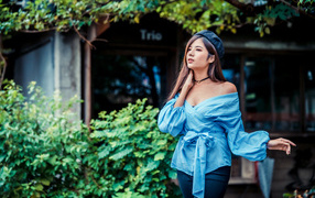 Девушка азиатка в синей рубашке и черном берете