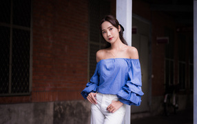 Девушка азиатка в белых брюках у дома