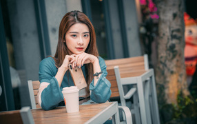Девушка азиатка сидит за столом в кафе с телефоном 