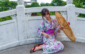 Asian girl sitting in a kimono with an umbrella