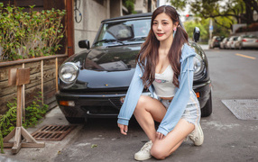 Девушка азиатка сидит возле машины 