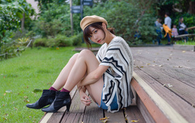 Девушка азиатка сидит в парке на лавке 