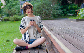 Девушка азиатка сидит с кофе в осеннем парке 