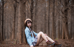 Девушка азиатка школьница сидит под деревом