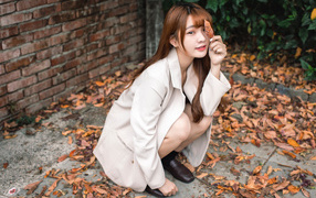 Красивая девушка азиатка на земле с опавшей листвой 