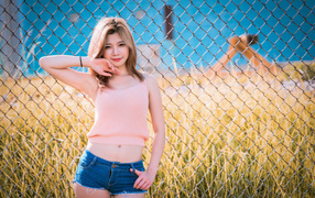 Красивая девушка азиатка стоит у железной сетки