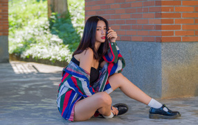 Красивая азиатка в рубашке у стены