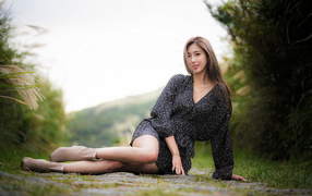 Красивая девушка азиатка в платье лежит на земле 