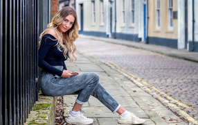 Красивая девушка блондинка сидит у забора