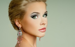 Красивая девушка блондинка с красивыми сережками на сером фоне