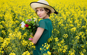 Красивая девушка в шляпе на поле с желтыми цветами летом