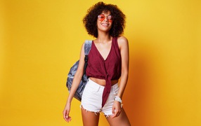 Красивая девушка в очках с рюкзаком на желтом фоне 