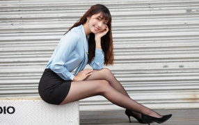 Красивая улыбающаяся девушка азиатка в черной юбке 