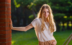 Красивая нежная девушка стоит у стены 