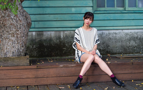 Красивая молодая девушка азиатка сидит у дома