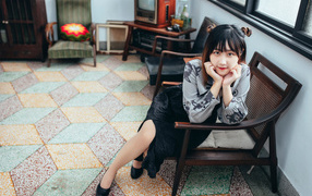 Красивая молодая азиатка сидит в кресле