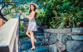 Милая девушка азиатка в платье стоит на ступеньках 