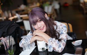 Милая девушка азиатка сидит за столиком