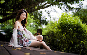 Милая девушка азиатка сидит на мосту