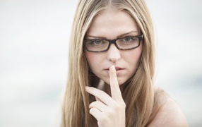 Девушка в очках с пальцем у лица