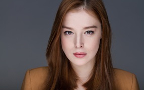 Рыжеволосая  молодая девушка на сером фоне