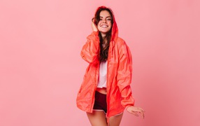 Улыбающаяся девушка в плаще на розовом фоне