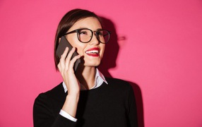 Улыбающаяся девушка с телефоном на розовом фоне