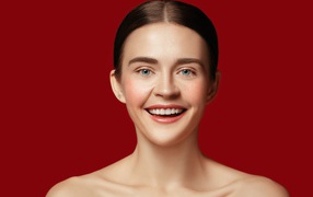 Улыбающаяся молодая девушка на красном фоне