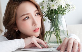 Молодая азиатка с букетом белой хризантемы в вазе